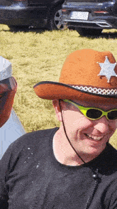 a man wearing a cowboy hat and sunglasses with a sheriff 's star on it