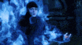 a man is surrounded by blue flames and smoke while standing in a dark room .