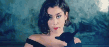 a woman in a black dress and red lipstick is holding a black cat in her hand .
