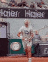 a man holding a tennis racquet in front of an ad for haier
