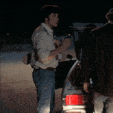 a man in a cowboy shirt is opening a bottle with a knife