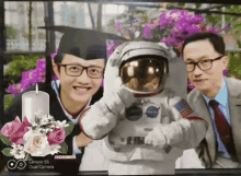 a man in a graduation cap and gown poses with an astronaut