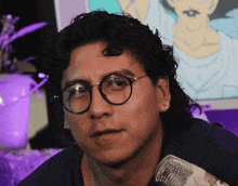 a man with curly hair wearing glasses and a microphone