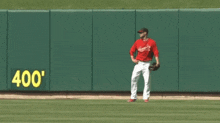 a baseball player stands on a field in front of a wall that says 400 '