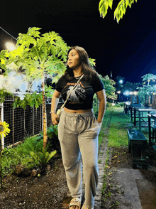 a woman wearing a black metallica t-shirt stands in a garden