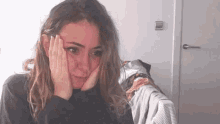 a woman is sitting on a bed with her hands on her face and looking at the camera .