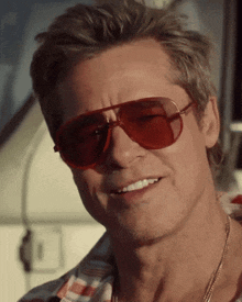 a close up of a man wearing red sunglasses and a plaid shirt