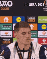 a man stands in front of a sign that says ' uefa 2025 ' on it