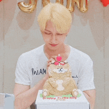 a man wearing glasses blows out a pink candle on top of a cat cake
