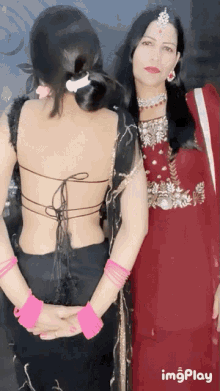 a woman in a red dress is standing next to a woman in a black top