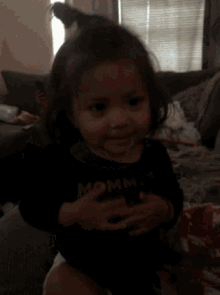 a little girl wearing a shirt that says mommy 's on it