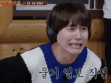 a man wearing headphones is making a funny face with a foreign language behind him