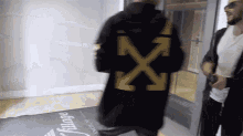 a man in a black coat with a yellow x on it