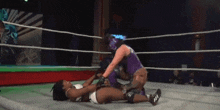 a wrestler in a purple outfit is wrestling another wrestler in a ring