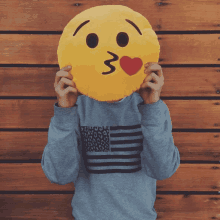 a person covering their face with a yellow smiley face