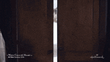 a man and a woman are standing in front of a hallmark ad