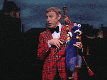 a man in a plaid jacket is holding a blue puppet