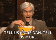 a man is holding a bucket of popcorn with the words tell us more dan tell us more below him