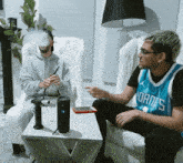 a man in a dallas jersey sits on a couch with another man