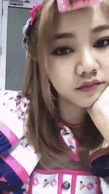 a close up of a girl 's face with her hand on her face