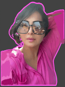 a woman wearing sunglasses and a pink shirt has her hand on her head