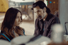 a man and a woman are sitting next to each other in a room