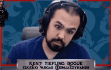 a man with a beard is wearing headphones and a name plate that says kent tiefling rogue