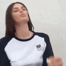 a woman is blowing a kiss while wearing a baseball shirt and a necklace .