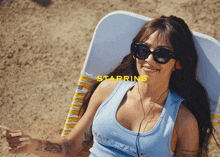 a woman wearing sunglasses and a blue tank top with the word starring on the bottom