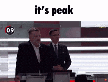 two men standing in front of a podium with the words " it 's peak " above them