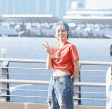 a woman with blue hair and a red shirt is giving the peace sign