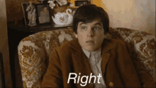 a man in a brown jacket is sitting in a chair with the word right written on his face