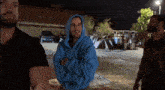 a man in a blue hoodie is standing in a parking lot with two other men .