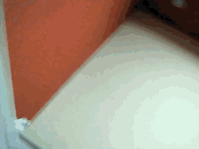 a corner of a room with an orange wall and a white shelf