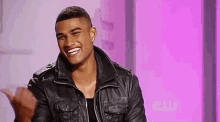 a man in a leather jacket is smiling and giving a thumbs up .