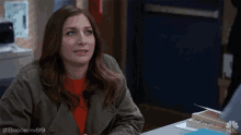 a woman sitting at a desk with the hashtag brooklyn99 on the bottom