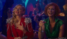 two women are sitting next to each other in a room and laughing .