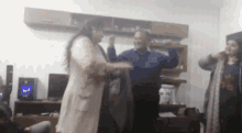 a group of people are dancing in a living room with a speaker in the background .