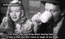 a man is drinking from a cup while a woman looks on .