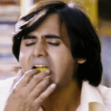 a man is eating a lemon with his hand in his mouth