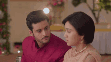 a man in a red shirt is looking at a woman in a pink dress