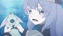 a girl with blue hair is holding a small rabbit in her hands