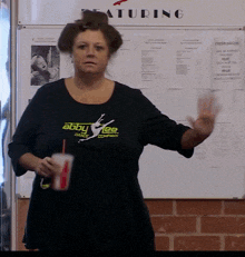 a woman wearing an abby lee dance shirt stands in front of a whiteboard
