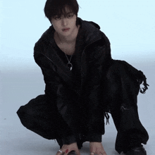 a person wearing a black jacket and pants kneeling down