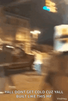 a blurry picture of a street at night with the words yall dont get cold cuz yall built like this mf on the bottom