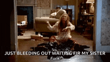 a woman is sitting on the floor in a living room with blood coming out of her clothes .
