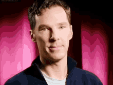 a close up of a man 's face with a pink curtain behind him .