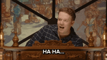a man is laughing in front of a painting and the words ha ha are visible
