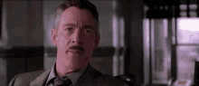 a man in a suit and tie is making a funny face while sitting in a room .
