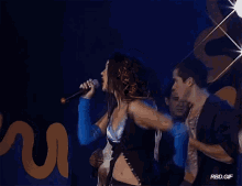 a woman singing in front of a sign that says ' rbd.gif '